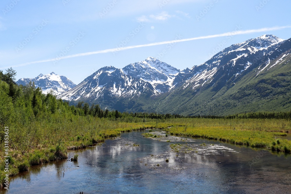 Landscape of a river surrounded by snowy mountains and greenery
