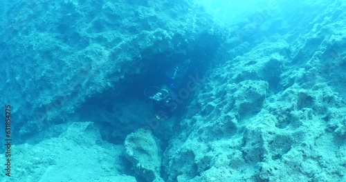 scuba divers explorig the reefs ad rocks enjoying the topography underwater photo