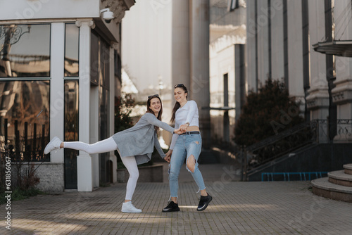 Photo of two young women dancing and having fun in the sunny city streets