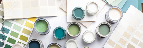 Tiny sample paint cans during house renovation, process of choosing paint for the walls, different green and beige colors, color charts on background, banner size