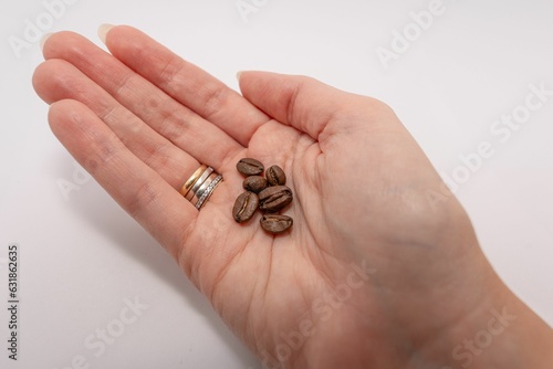 Closeup shot of a female hand holding small coffee beans isolated on a pristine white background.
