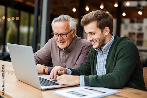 Mature male businessman and his senior father looking at and studying monthly finances on laptop computer