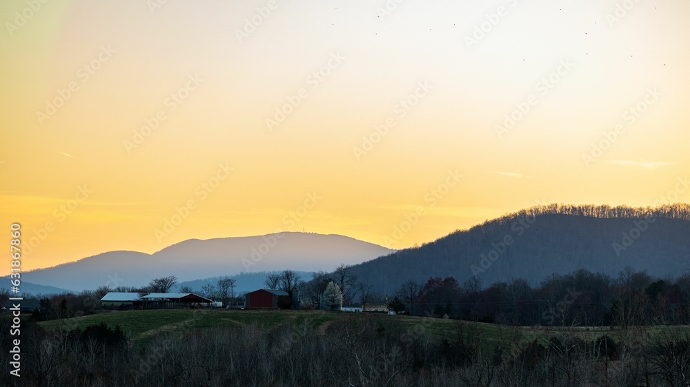 Tranquil view of a mountain valley and a small town surrounded by woodland at sunset