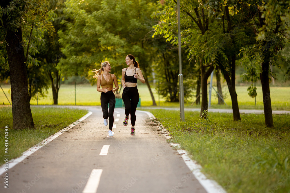 Obraz premium Two pretty young women running on the lane in the park