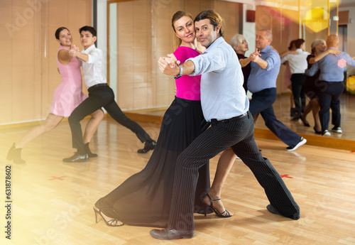 Obraz na plátne Active middle-aged pair practicing ballroom dance in training hall during dancing-classes