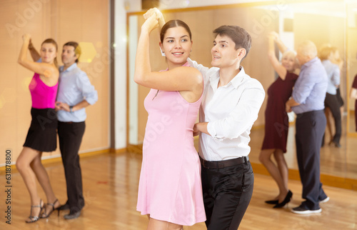 Cheerful couple of young dance lovers visiting group choreography class, practicing vigorous lindy hop moves. Concept of active lifestyle