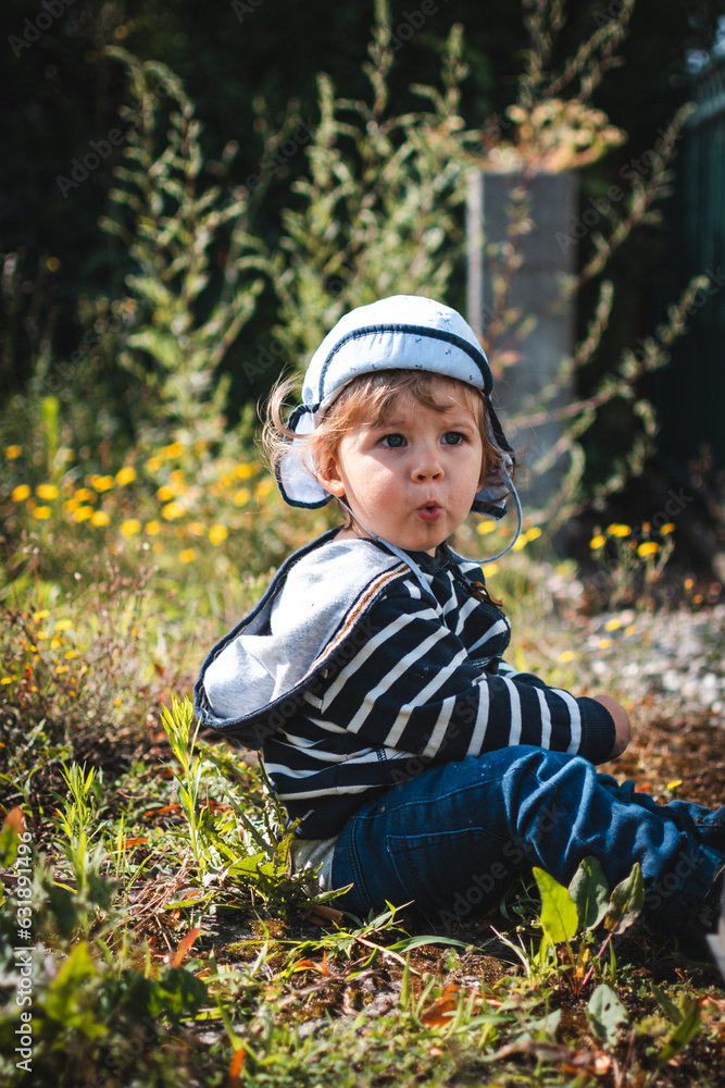Kind sitzt im Gras und macht einen lustigen Gesichtsausdruck Kind sitzt im Gras und macht einen lustigen Gesichtsausdruck