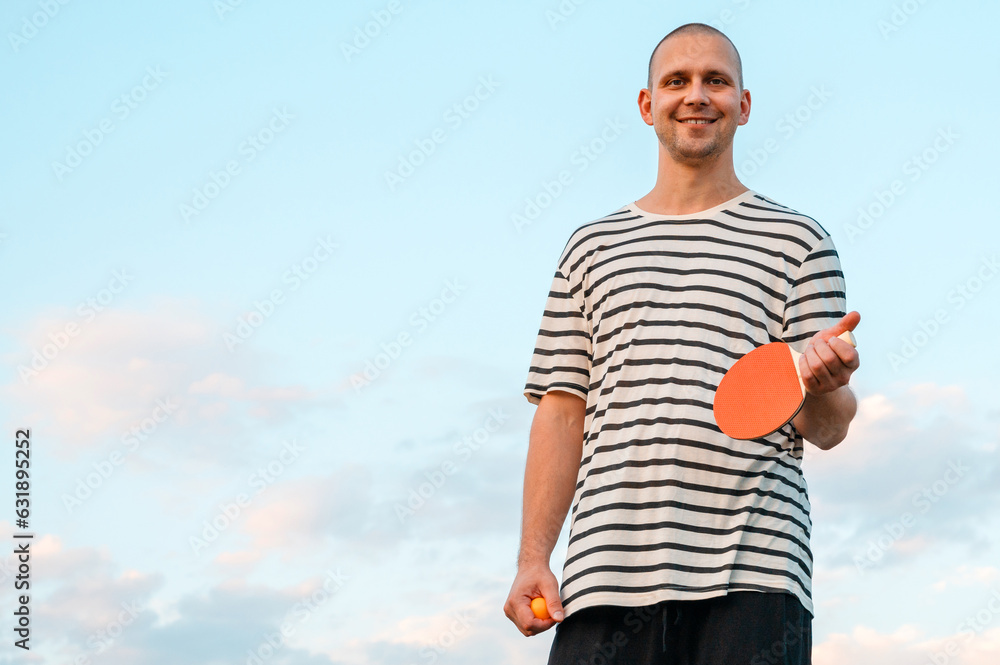 man holding ping pong paddle table tennis paddle on sky background. Mock-up copy space. Poster about sport and healthy life. man holding ping pong paddle table tennis paddle on sky background. Mock-up copy space. Poster about sport and healthy life.