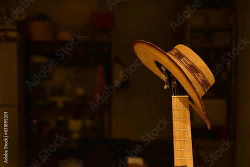 Sombrero descanzando sobre güitarra. Sombrero sobre la clavija de la güitarra, fondo desenfocado oscuro. photo