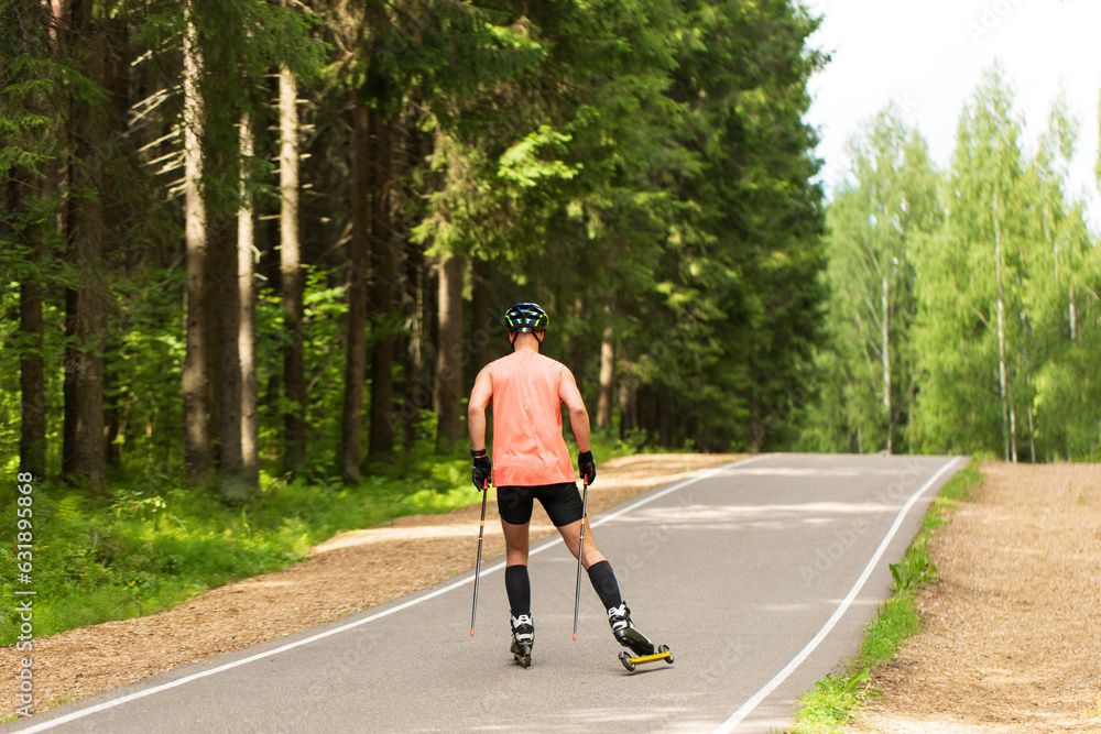 Fototapeta premium A man rides roller skis in a summer park.Cross country skiing.