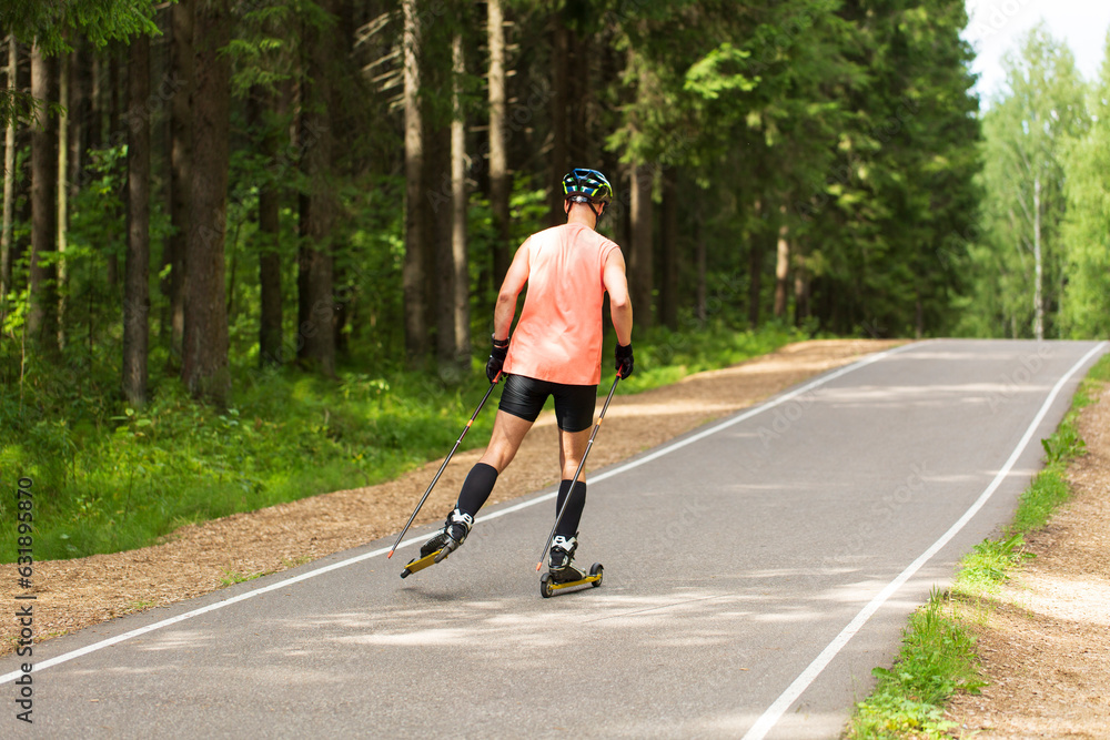 Fototapeta premium A man rides roller skis in a summer park.Cross country skiing.