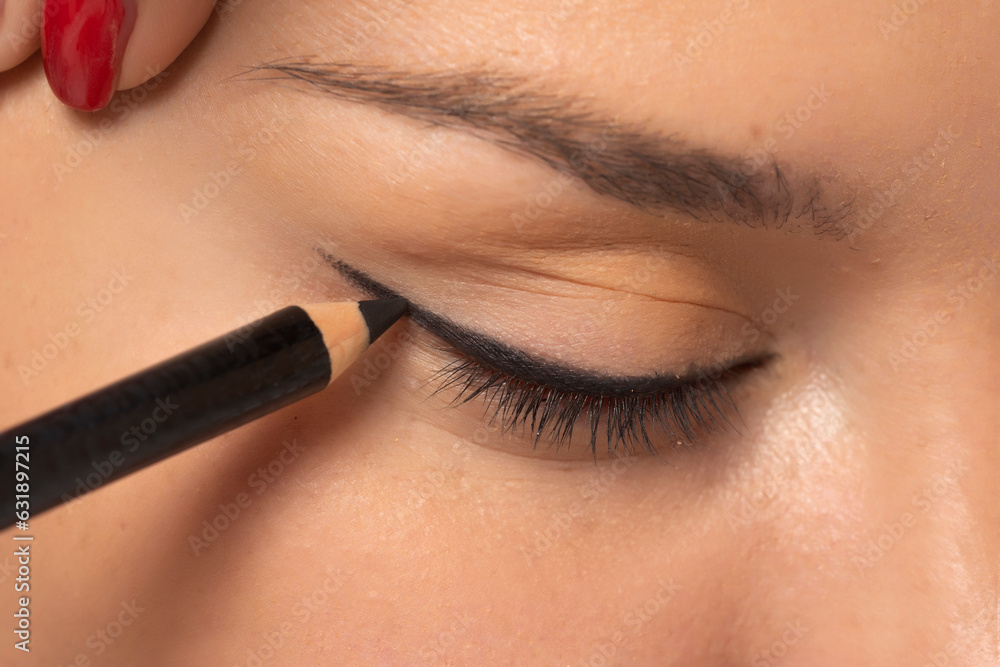 woman applying cosmetic pencil on the eye