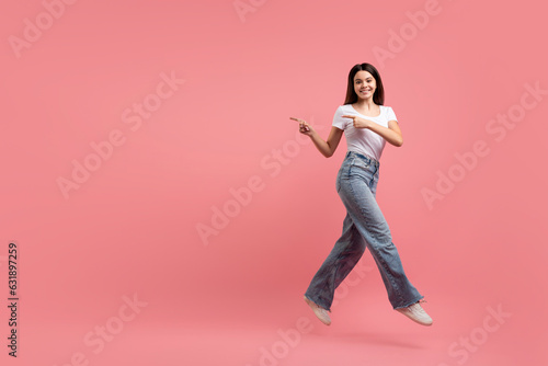 Look At This. Cherful teen girl jumping up and pointing aside photo