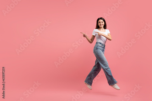 Obraz na płótnie Look At This. Cherful teen girl jumping up and pointing aside