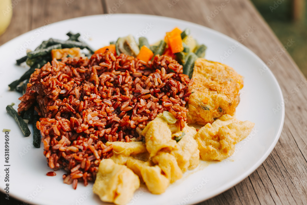 Brown delicious rice with vegetables and egg on a white plate close-up. Asian lunch with beans and tofu close-up Brown delicious rice with vegetables and egg on a white plate close-up. Asian lunch with beans and tofu close-up