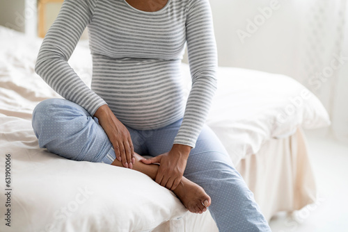 Pregnancy and health problems. Black pregnant woman massaging her swollen foot