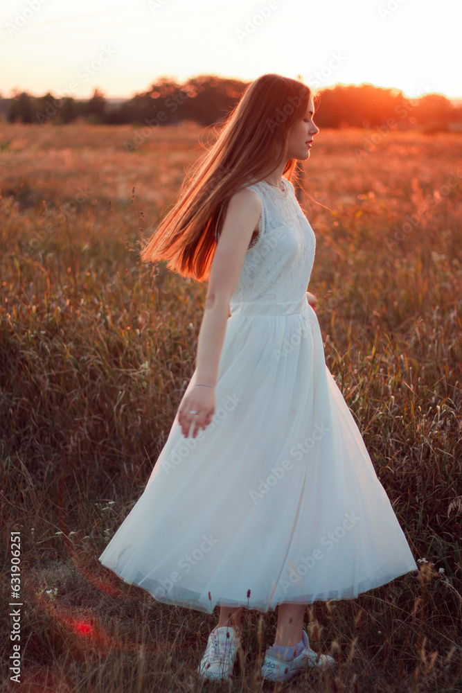 A beautiful pretty girl is dancing on a field at sunset in a white dress. Happy woman. Concept. Bride A beautiful pretty girl is dancing on a field at sunset in a white dress. Happy woman. Concept. Bride