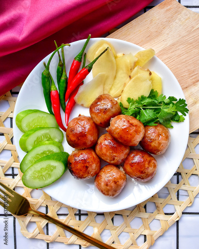 Isaan sausages on a white plate With cucumber, chilli, ginger and coriander ,top view ,Thai call sai krok isan