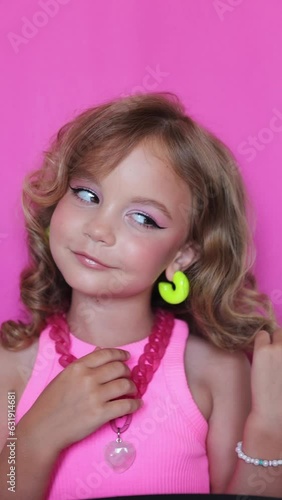 cute girl make-up on camera, in pink clothes on pink background, little blogger and makeup artist, vertical video
