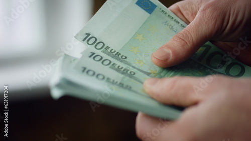 Man counting hundred euros bills indoors close up. Hands calculating banknotes.
