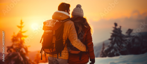 Couple enjoying the sunset on a winter day while skiing, hiking or snowshoeing in nature. Snow covering the trees and ground. Shallow field of view.