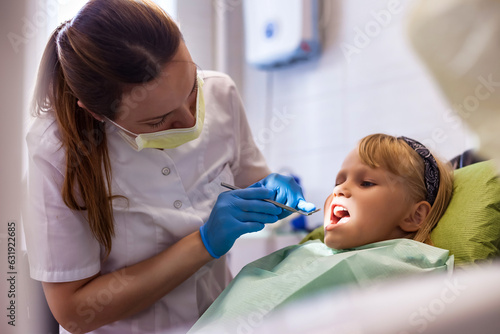 Dentist doing teeth checkup at dental office for adorable girl in children dentistry. Dentist doctor having examining little girl 5-6 year old teeth in clinic  close-up. Copy ad text space poster
