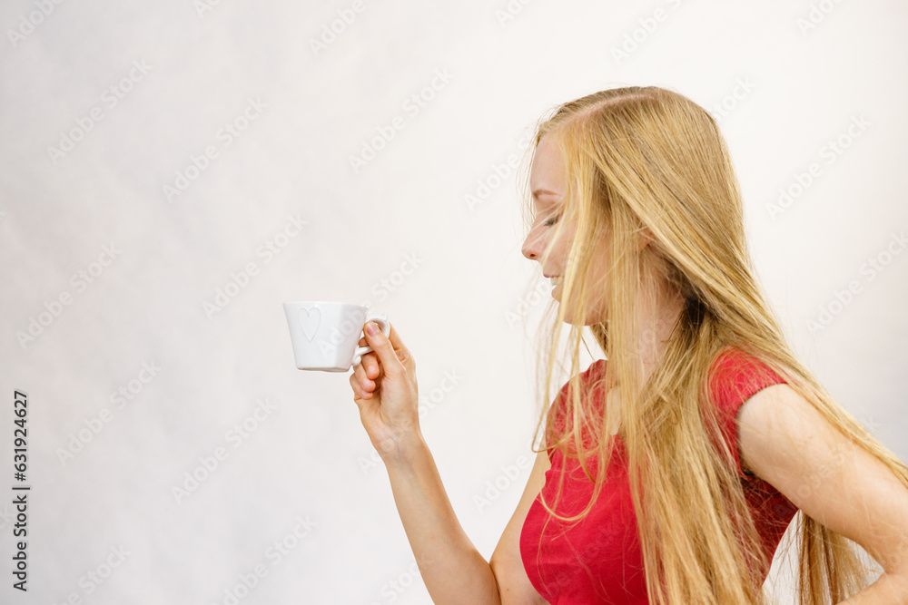 Blonde girl blowing hair holds coffee cup Blonde girl blowing hair holds coffee cup