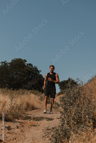 Young male athlete in sports clothing running down the footpath outdoors