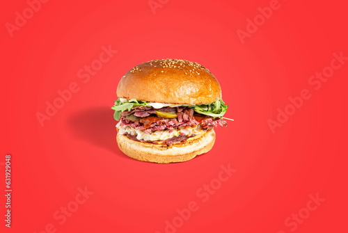 Delicious burger with sliced ​​roast beef or pastrami with lettuce, tomato, gherkin and mayonnaise. Advertising for a restaurant. The image is in full focus, front to back. Clipping path. photo