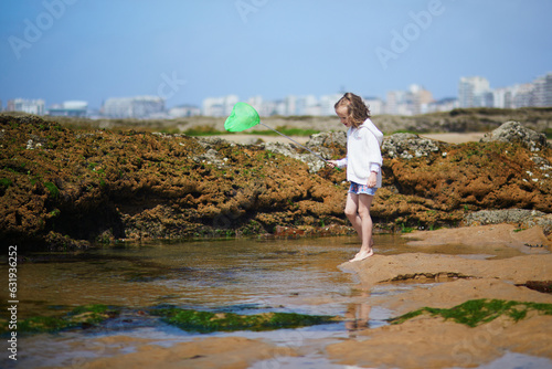 Adorable preshooler girl playing with scoop net on the beach at Atlantic coast of Brittany, France photo