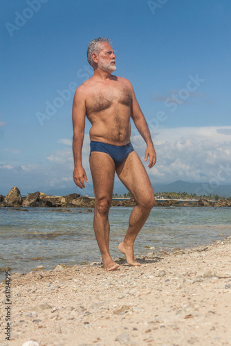 Fényképezés mature man in the tropical beach with blue speedo