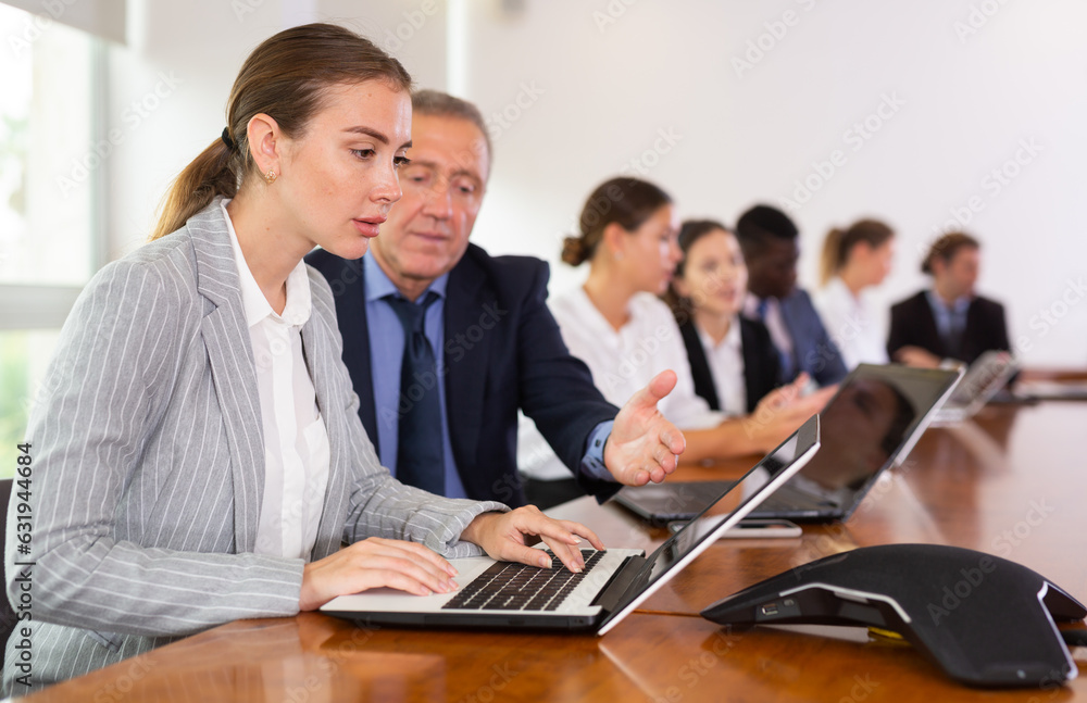 Fototapeta premium Mature businessman prompts and helps businesswoman during a business meeting