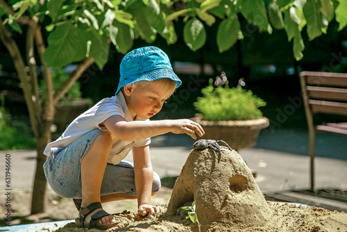 A little boy plays alone in the sandbox.