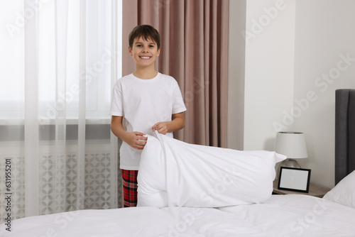Boy changing pillowcase in bedroom. Domestic chores