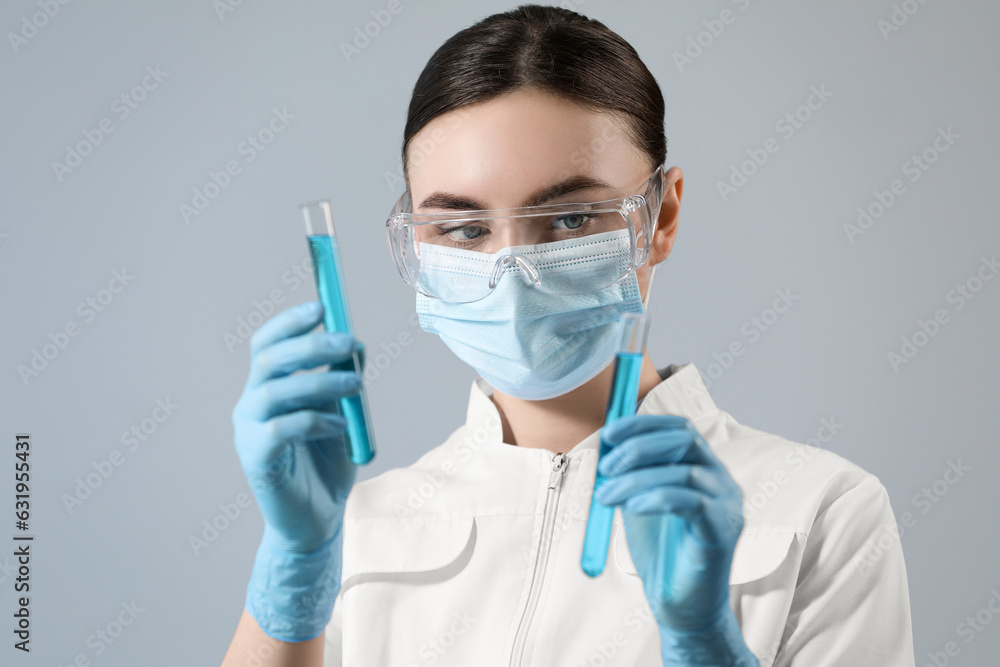 Scientist holding test tubes with samples on grey background Scientist holding test tubes with samples on grey background