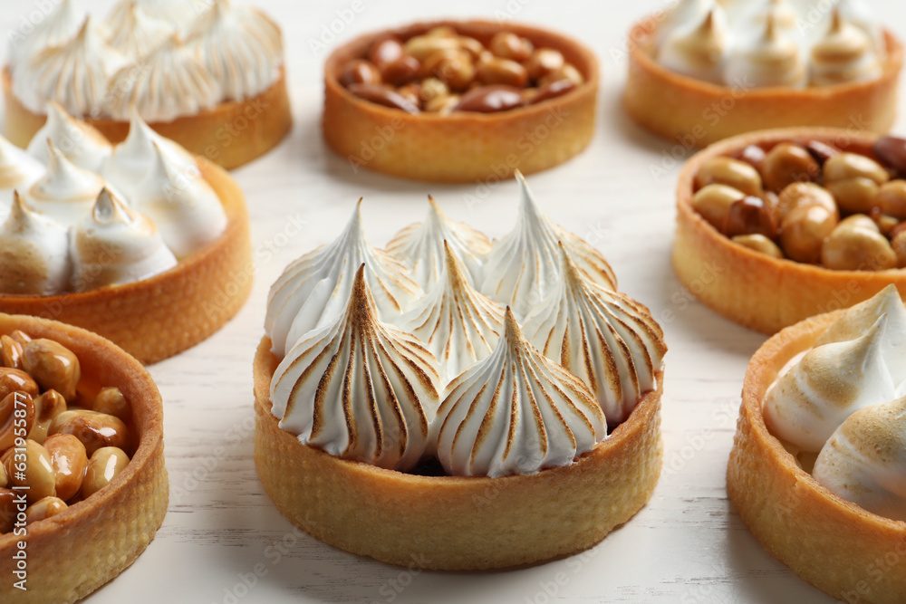 Many different tartlets on white wooden table, closeup. Delicious dessert