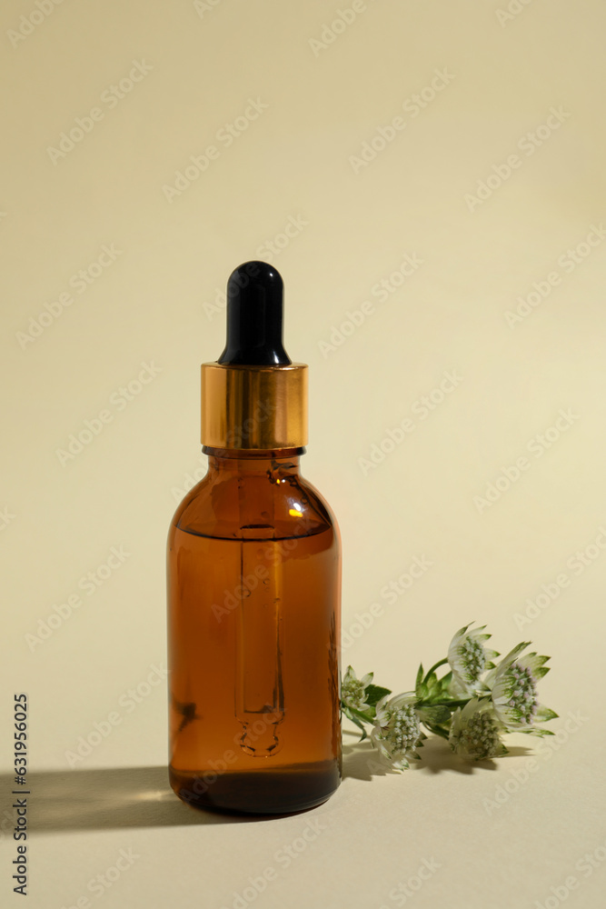 Bottle with cosmetic oil and flower on beige background Bottle with cosmetic oil and flower on beige background
