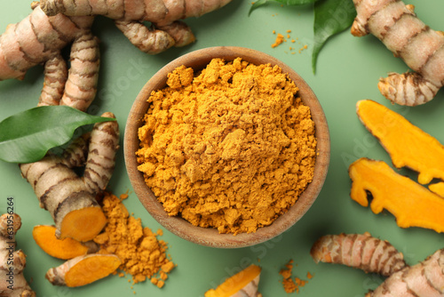 Aromatic turmeric powder, raw roots and leaves on green background, flat lay