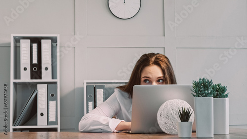 Hiding freelancer. Laptop work. Lazy woman scared of boss pretending busy using computer looking with frightened eyes sitting at office workplace.