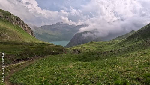 Green alpine meadows and hills surrounding lago vanino a turquoise lake in the alps of north italy. Hiking on the grand traverse delle alpi photo