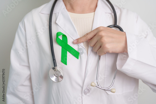 Doctor with green Ribbon for world Mental Health Day, Liver, Gallbladders, bile duct, cervical, kidney Cancer and Lymphoma Awareness month. Healthcare and world cancer day concept photo