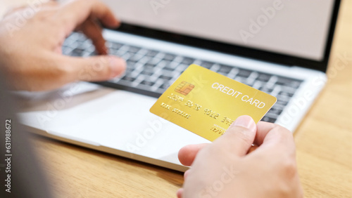 Man hand holding credit card for shopping online by laptop computer