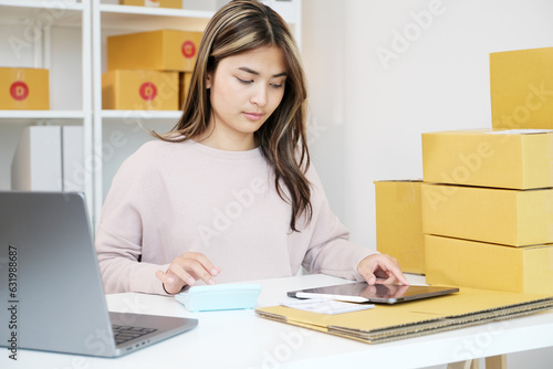Small business owner checking product stock by laptop computer at home office