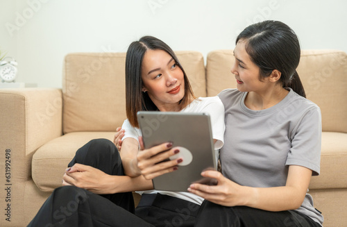 Moment lesbian LGBTQ woman couple sharing love and play social media with tablet. Good relationship time lesbian couple same-sex marriage. LGBTQ pride month, Pride Event.
