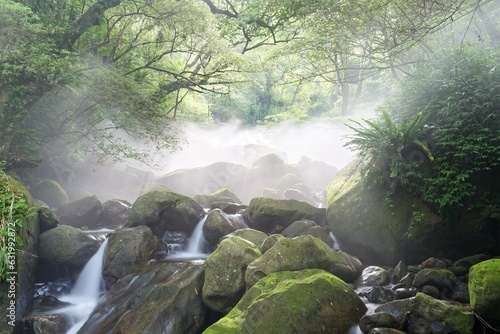 Beautiful river scenery of Taiwan in springtime, with refreshing cascades of a stream flowing down the mossy rocks in a mysterious forest and sunbeams shining through the misty air in lavish greenery