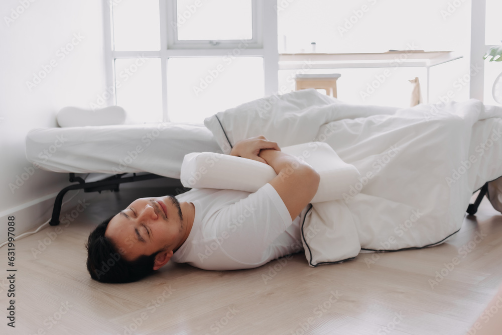 Asian man falling down from the bed lying on the floor at home. Asian man falling down from the bed lying on the floor at home.