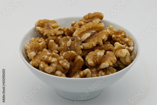 A bowl of peeled walnuts isolated on white background