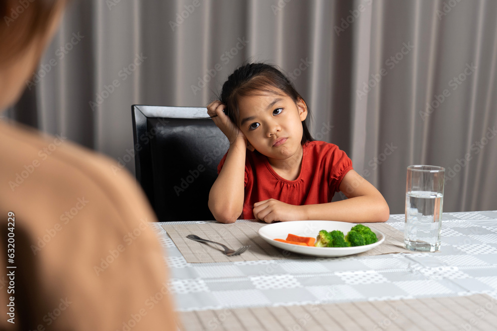 Mother is telling her cute kid eat useful vegetables but the child refuses to eat.