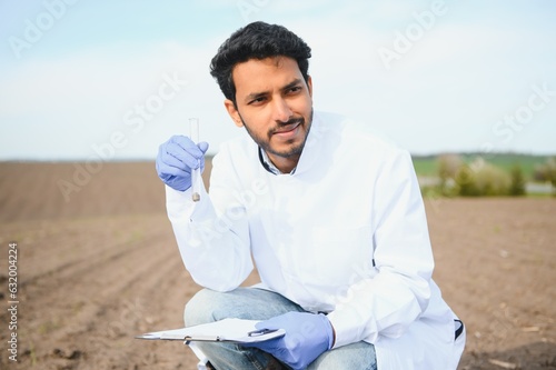 Soil Testing. Indian Agronomy Specialist taking soil sample for fertility analysis. Hands in gloves close up. Environmental protection, organic soil certification, field work, research