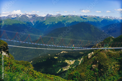 woman rouring walking on rope suspension bridge in caucasus mountains, Russia, Rosa Khutor resort